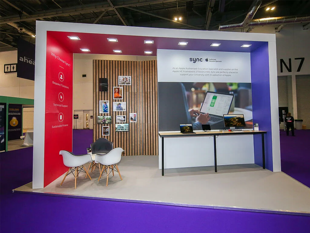 A bespoke, angular exhibition stand for Sync, using their red and purple branding across the stand elements